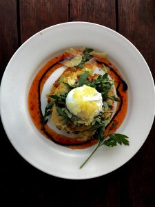 Breakfast of corn fritters with a poached egg.